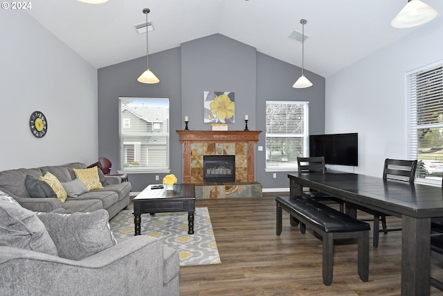 living room featuring dark hardwood / wood-style floors, a stone fireplace, and lofted ceiling