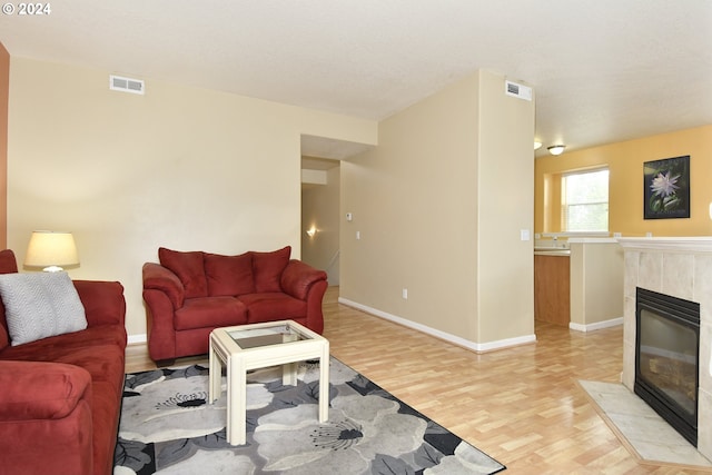 living room featuring light wood-type flooring and a tiled fireplace