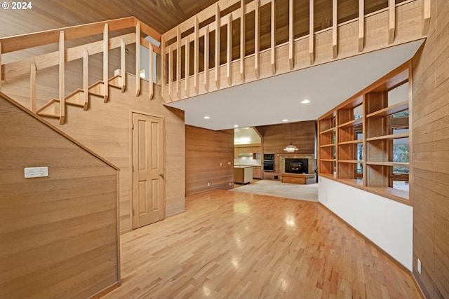 92932 Paschelke Rd, Marcola, OR 97454 - unfurnished living room with wood walls, a glass covered fireplace, a towering ceiling, and wood finished floors