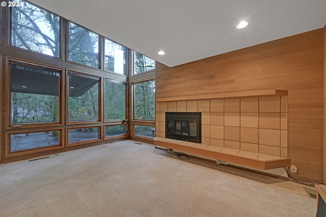 unfurnished living room with recessed lighting, visible vents, light carpet, wooden walls, and a tile fireplace