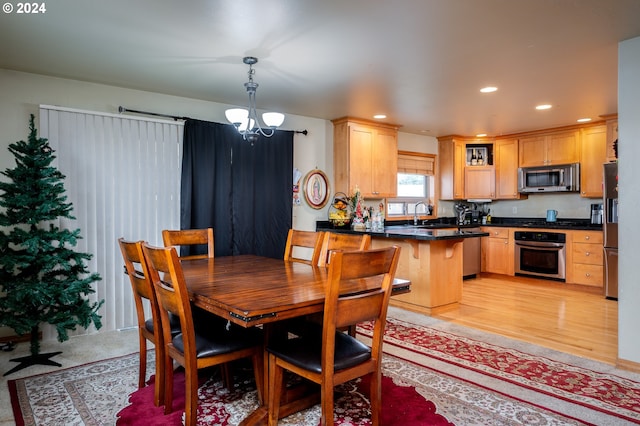 dining space with sink, light hardwood / wood-style floors, and a notable chandelier