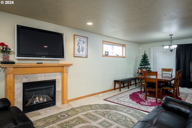 carpeted living room featuring a chandelier, a textured ceiling, and a tiled fireplace