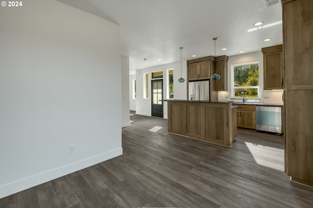 kitchen featuring a kitchen island, decorative light fixtures, sink, dark hardwood / wood-style flooring, and stainless steel appliances