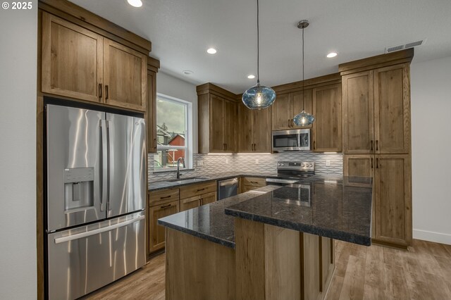 kitchen featuring light hardwood / wood-style floors, stainless steel appliances, sink, and dark stone counters