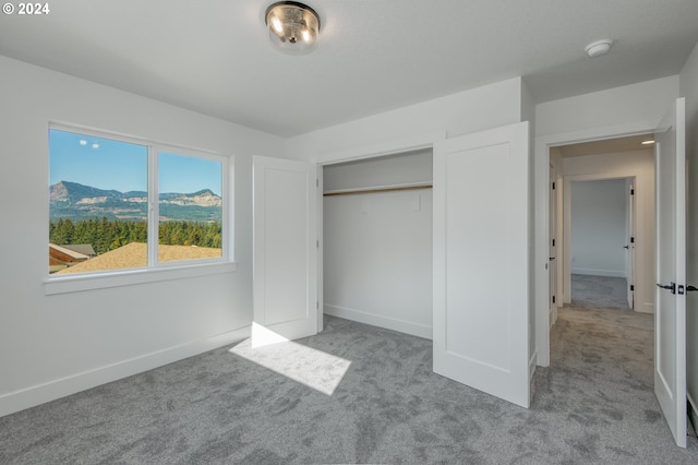 unfurnished bedroom with a mountain view, light colored carpet, and a closet