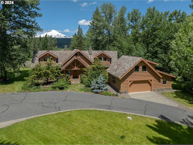 log-style house featuring a mountain view, a garage, and a front lawn