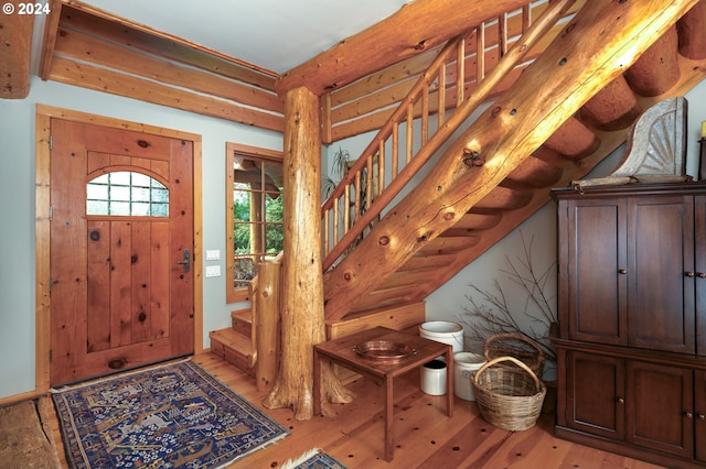 entrance foyer with light wood-style flooring, log walls, and stairs