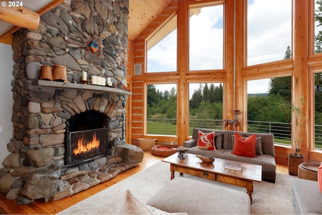 living area featuring beamed ceiling, high vaulted ceiling, wood finished floors, wooden ceiling, and a fireplace