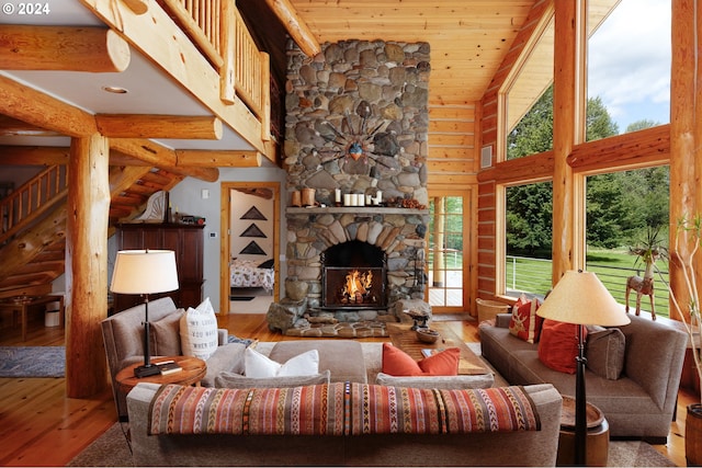 living area featuring log walls, a stone fireplace, hardwood / wood-style floors, and wooden ceiling