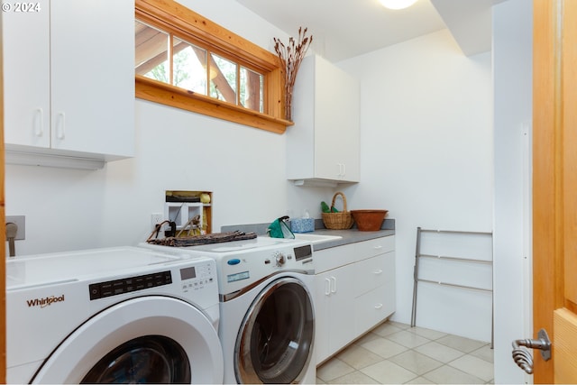 washroom featuring light tile patterned floors, cabinet space, and washing machine and clothes dryer