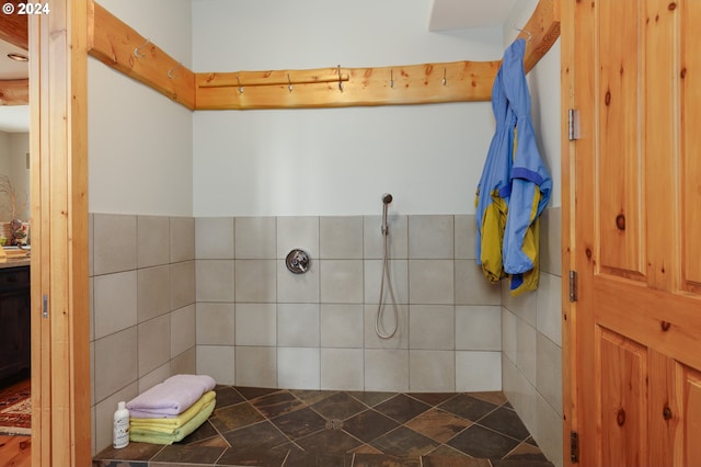 full bathroom with a wainscoted wall, tile walls, and tiled shower