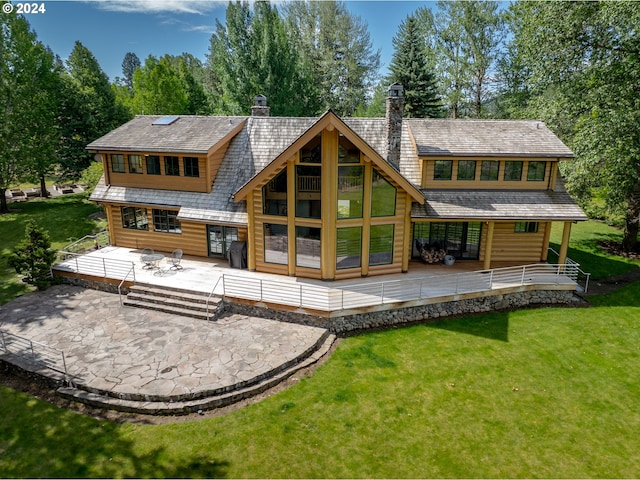 rear view of house featuring a deck, a yard, a patio area, and a chimney