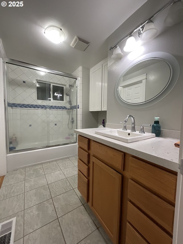 bathroom with tile patterned floors, vanity, and combined bath / shower with glass door