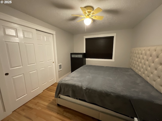 bedroom with ceiling fan, a closet, a textured ceiling, and light hardwood / wood-style flooring