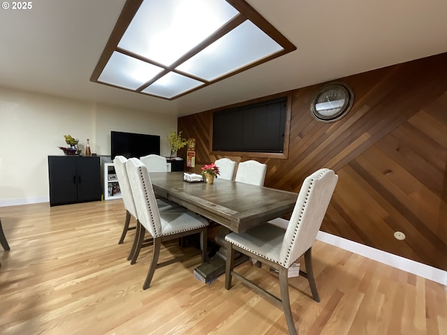 dining area featuring wood walls and light wood-type flooring