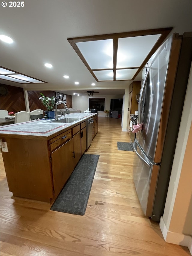 kitchen featuring an island with sink, stainless steel appliances, light hardwood / wood-style floors, and sink