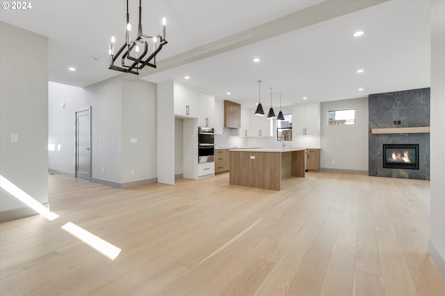 kitchen featuring a kitchen island, double oven, open floor plan, and white cabinets