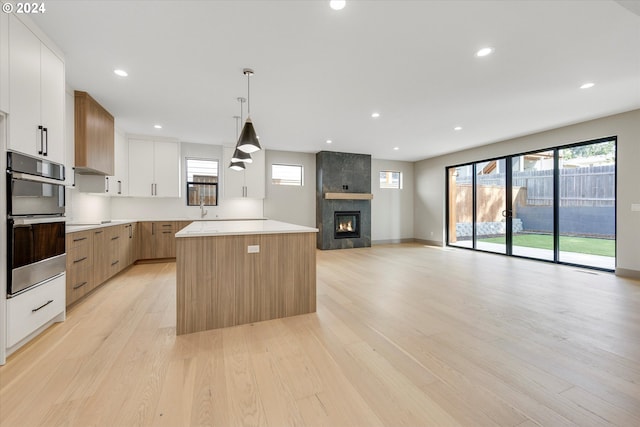 kitchen with double oven, modern cabinets, light countertops, and a kitchen island