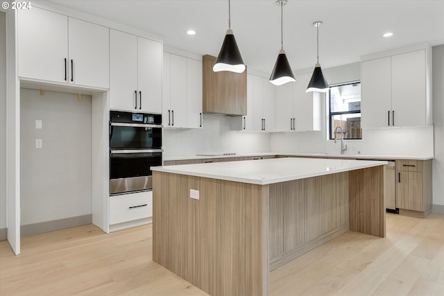 kitchen with stainless steel dishwasher, double oven, light wood-style flooring, and a center island