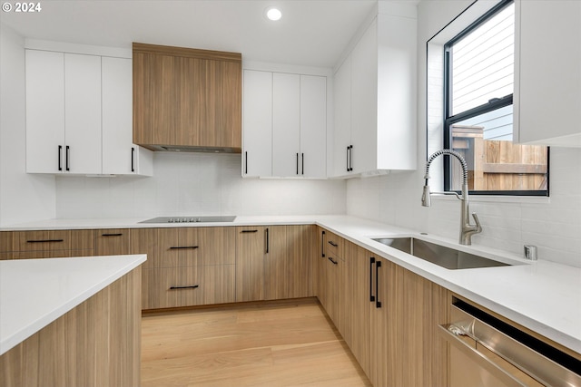 kitchen with backsplash, light countertops, stainless steel dishwasher, black electric cooktop, and a sink