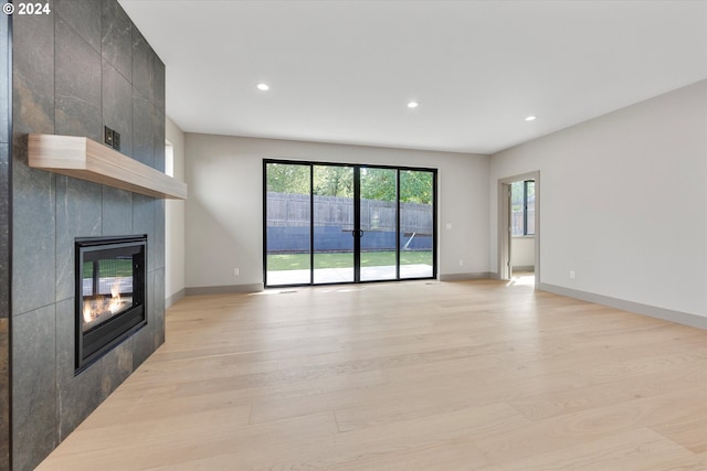 unfurnished living room with recessed lighting, a fireplace, light wood-type flooring, and baseboards