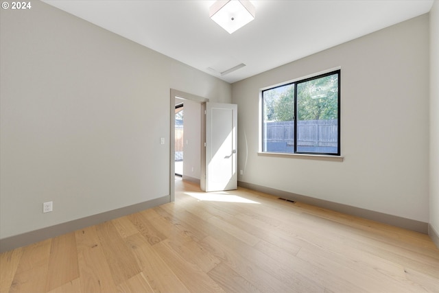 empty room with baseboards, visible vents, and light wood finished floors