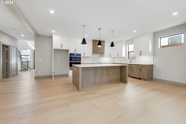 kitchen with custom exhaust hood, dobule oven black, stainless steel dishwasher, light wood-type flooring, and a center island