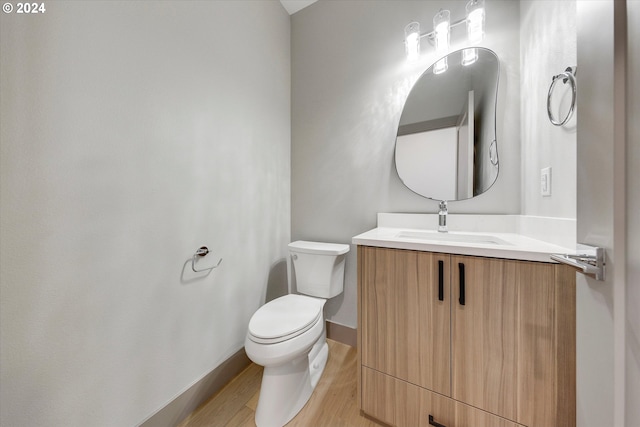 bathroom with baseboards, toilet, wood finished floors, and vanity