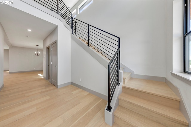 staircase featuring baseboards, a notable chandelier, and wood finished floors