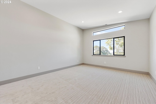 unfurnished room with recessed lighting, baseboards, and light carpet