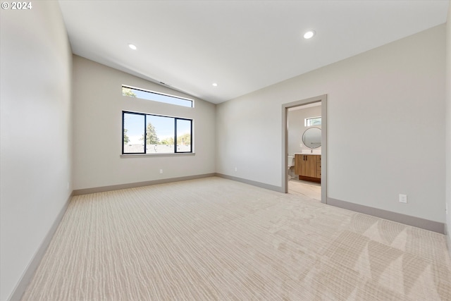 unfurnished bedroom featuring light carpet, ensuite bath, recessed lighting, baseboards, and vaulted ceiling