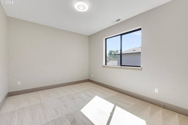 empty room with light colored carpet, baseboards, and visible vents