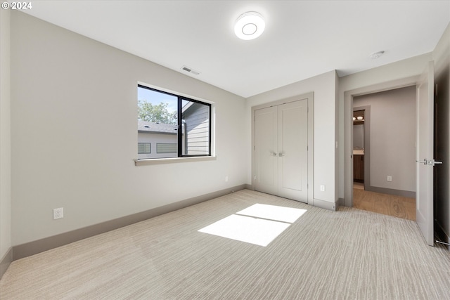 unfurnished bedroom featuring visible vents, carpet flooring, baseboards, and a closet