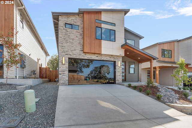 modern home featuring fence and stone siding