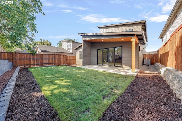 rear view of property featuring central air condition unit, a patio, a lawn, and a fenced backyard