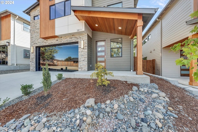 doorway to property featuring a porch, stone siding, and driveway