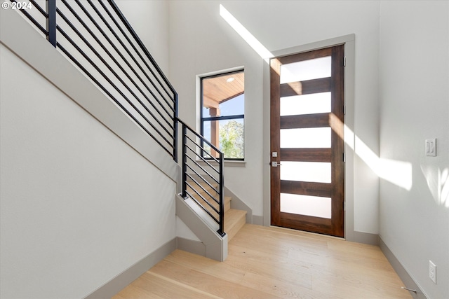 foyer entrance with baseboards, wood finished floors, and stairs