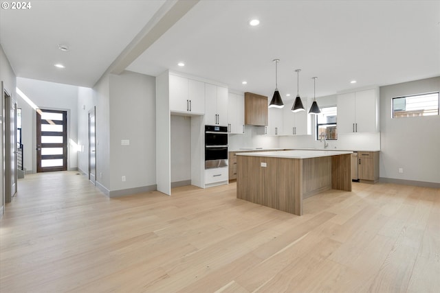 kitchen with recessed lighting, a kitchen island, light wood-style flooring, and white cabinets