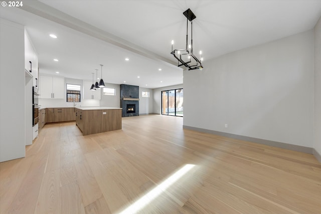 kitchen featuring a center island, a large fireplace, open floor plan, light wood-type flooring, and light countertops