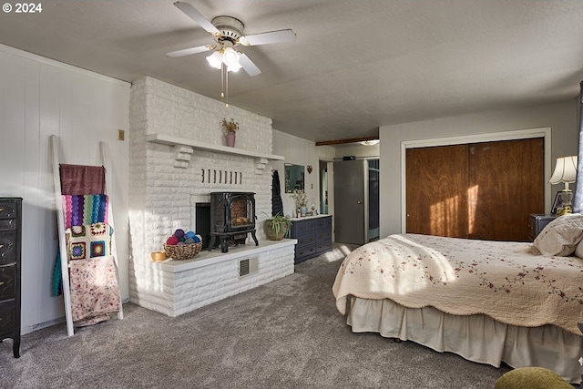 carpeted bedroom featuring a closet, a wood stove, and ceiling fan