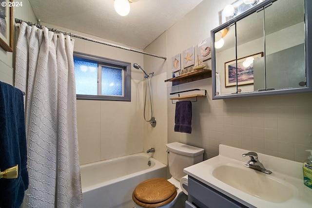 full bathroom featuring a textured ceiling, vanity, shower / bath combo with shower curtain, tile walls, and toilet