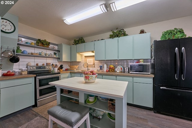 kitchen with hardwood / wood-style floors, backsplash, and stainless steel appliances