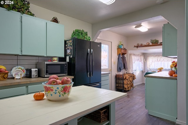 kitchen with dark hardwood / wood-style floors, black fridge, and tasteful backsplash