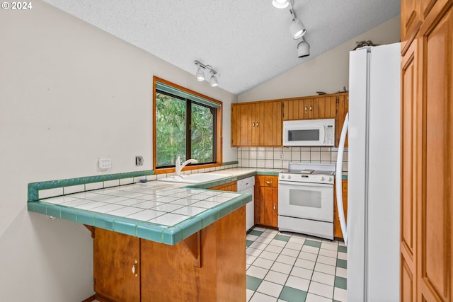 kitchen with sink, tile countertops, kitchen peninsula, vaulted ceiling, and white appliances