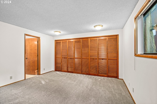 unfurnished bedroom featuring carpet flooring, a closet, and a textured ceiling