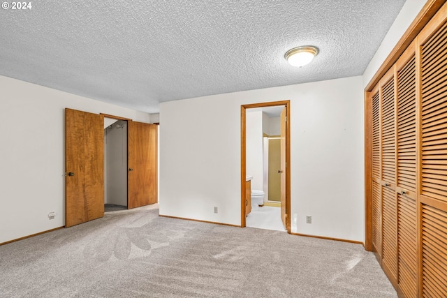 unfurnished bedroom with light carpet, a textured ceiling, connected bathroom, and a closet