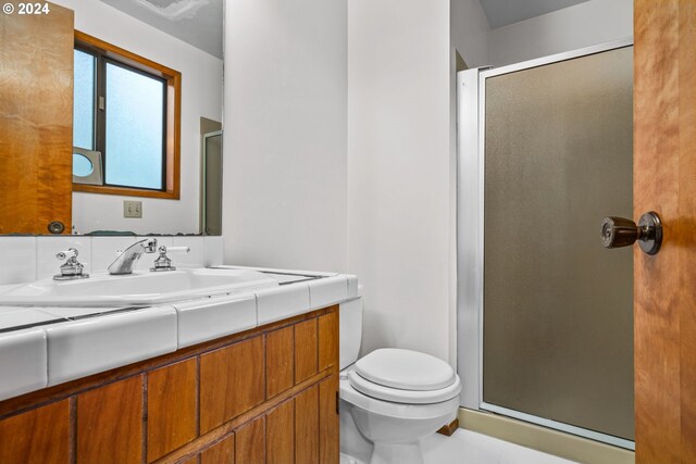 bathroom with vanity, toilet, and a shower with door