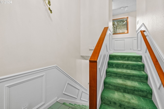 staircase featuring a textured ceiling and track lighting