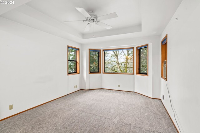 carpeted spare room with ceiling fan and a raised ceiling