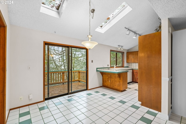 kitchen with stainless steel dishwasher, kitchen peninsula, lofted ceiling with skylight, decorative light fixtures, and a breakfast bar area